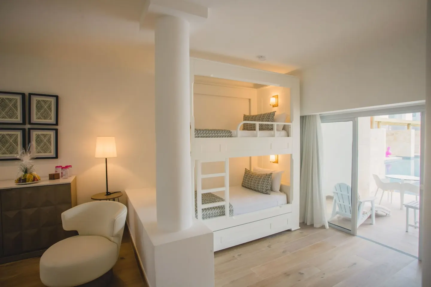 Family guest room with bunk beds, chair, and terrace doors at Princess Family Club Bavaro.