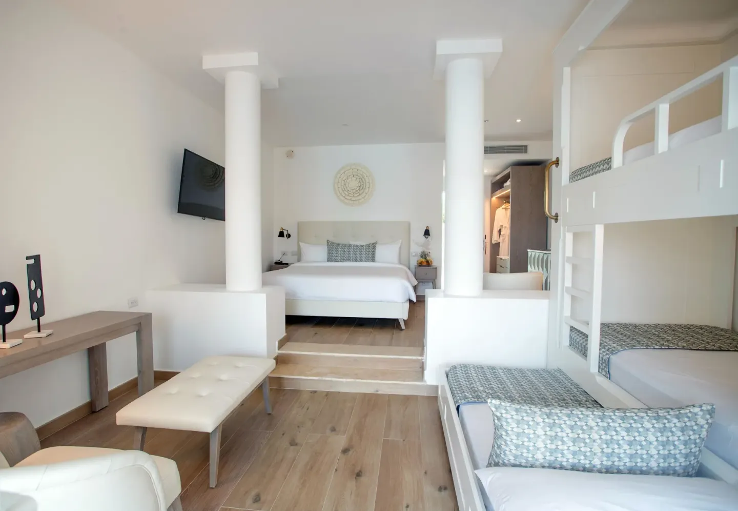 Family suite with king bed, bunk beds, and seating area at Princess Family Club Bavaro.