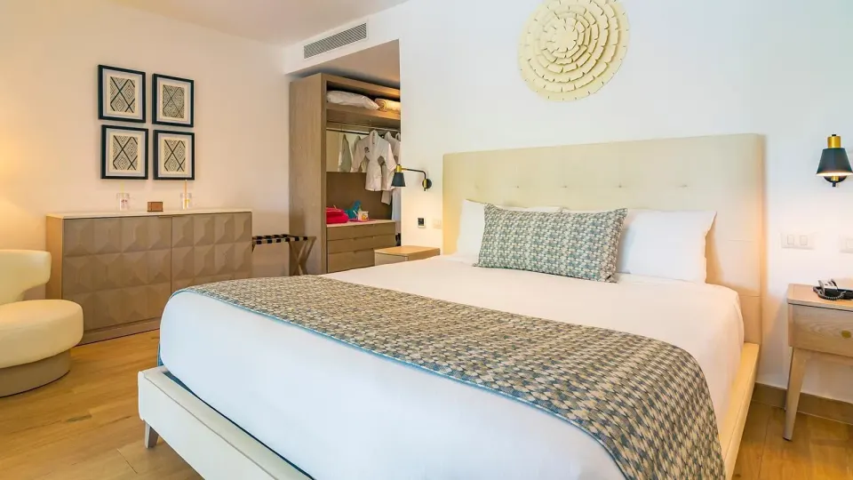 King bed guest room with open closet and dresser at Princess Family Club Bavaro.