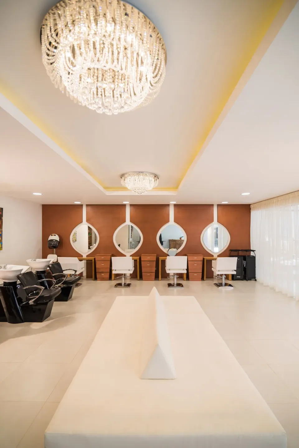 Salon with styling chairs, wash stations, and chandeliers at Princess Family Club Bavaro.