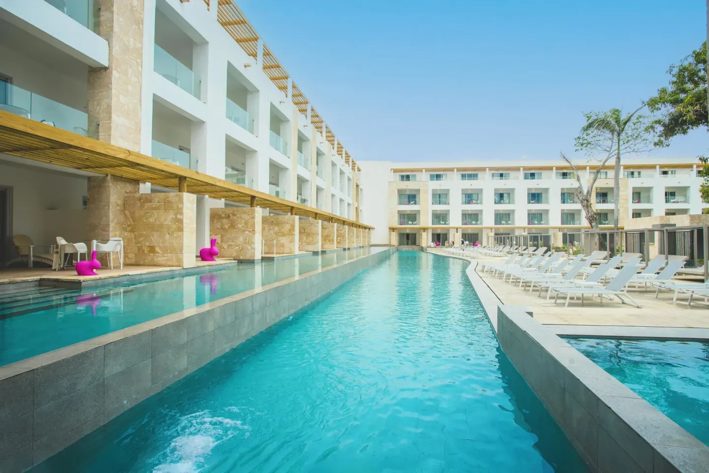 Long swim-up pool lined with loungers and resort buildings at Princess Family Club Bavaro.