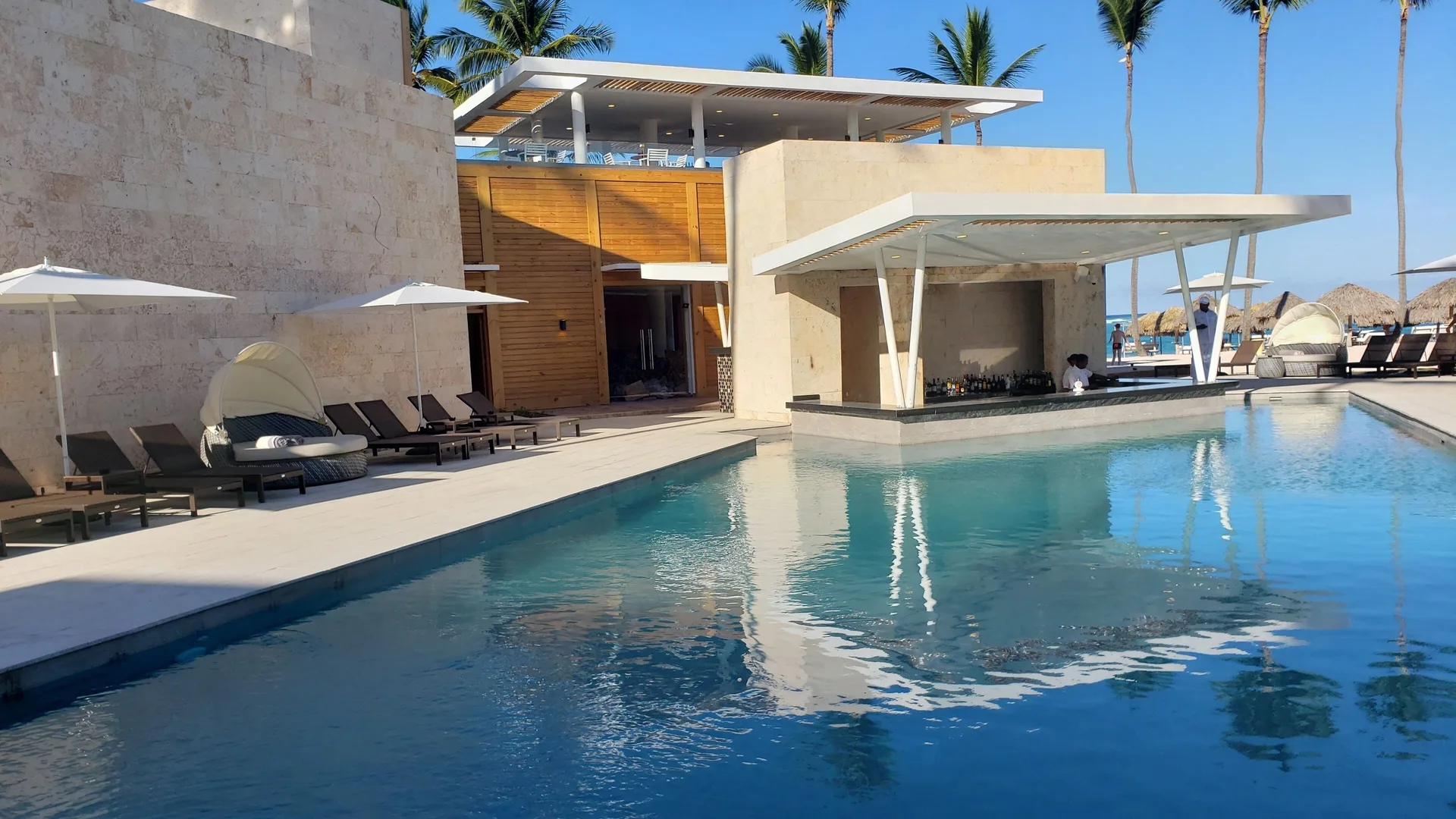 Poolside bar pavilion and lounge chairs by the water at Princess Family Club Bavaro.