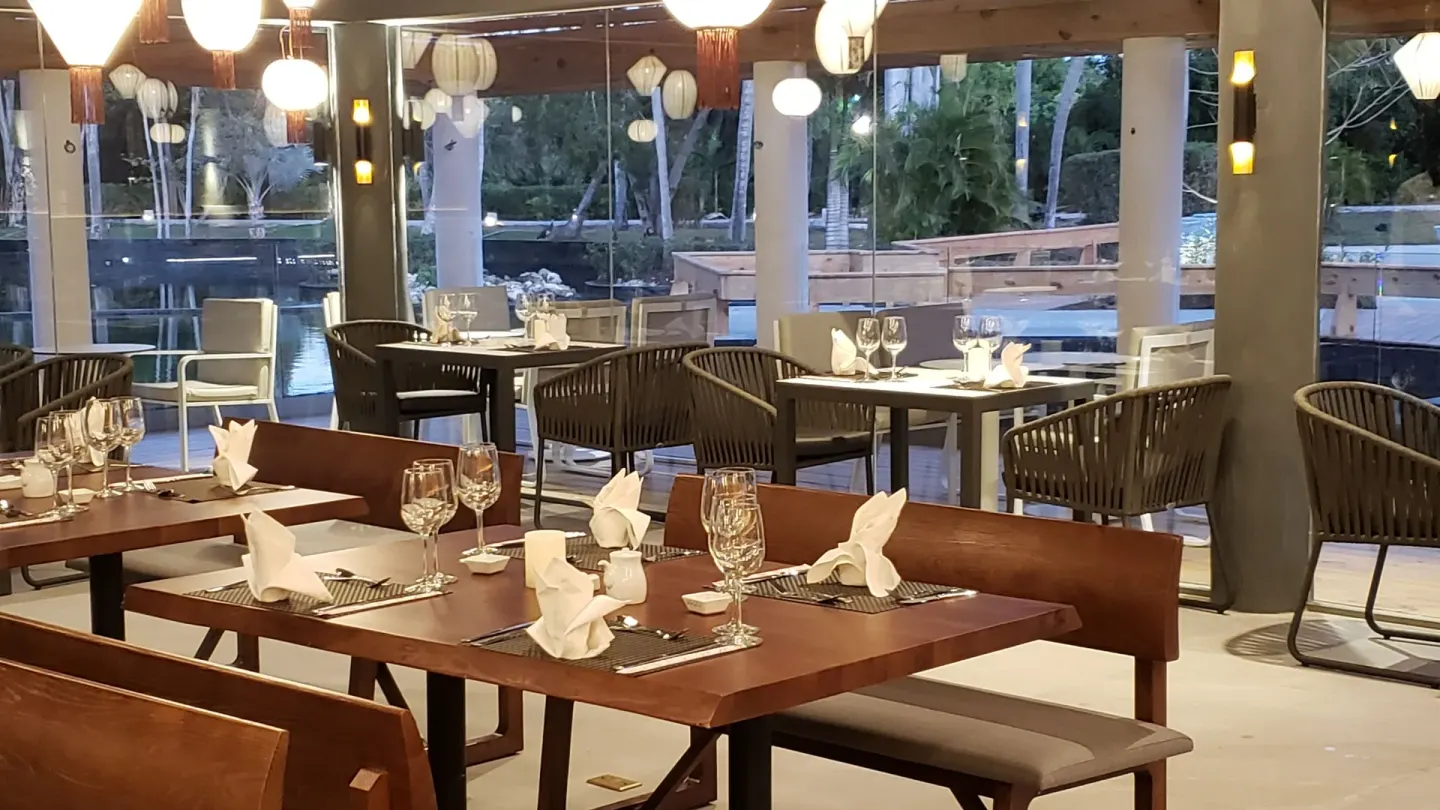 Restaurant tables set beside large windows and water views at Princess Family Club Bavaro.
