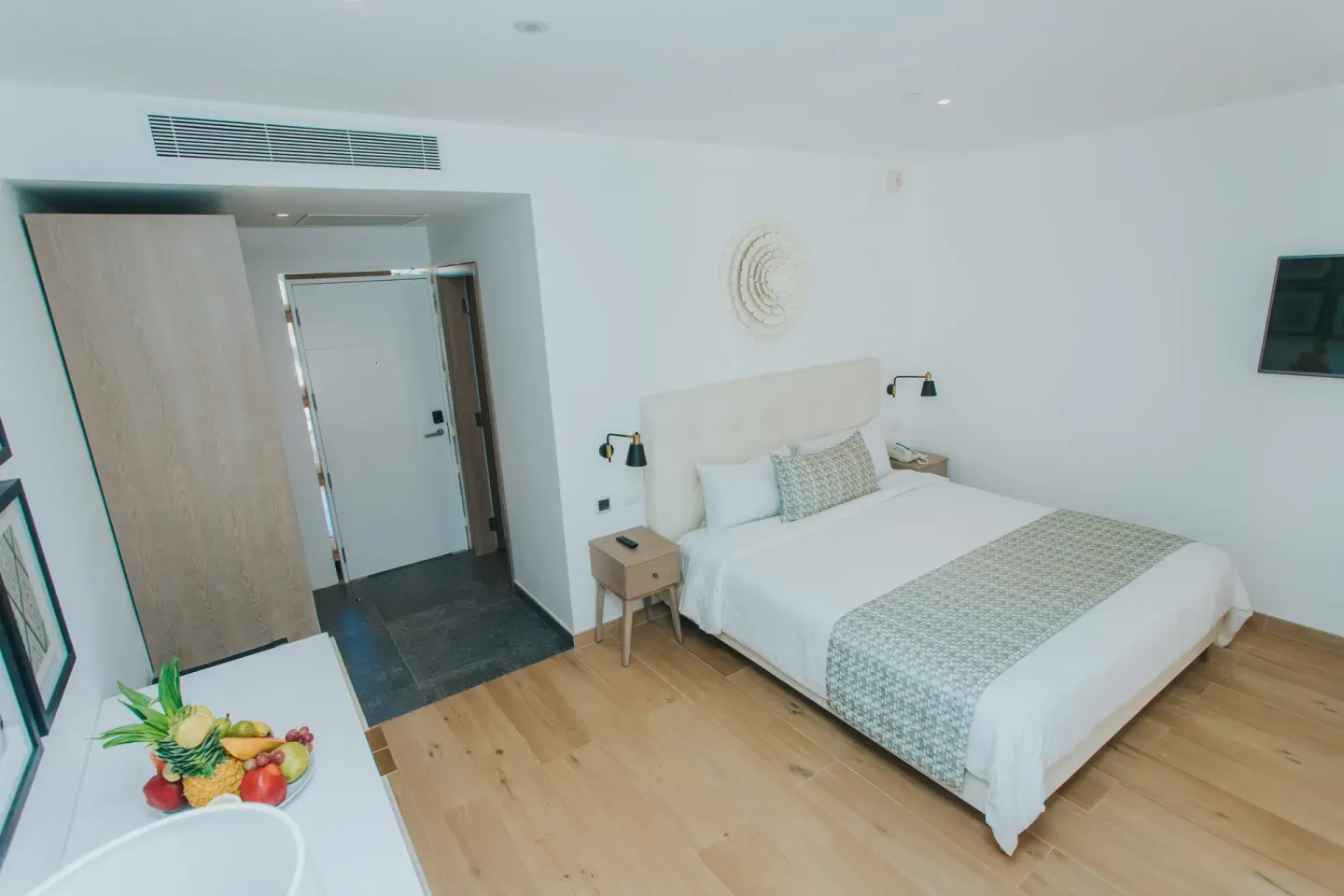 Family Club Junior Suite Swimout king bed, entry, and TV at Princess Family Club Bavaro.