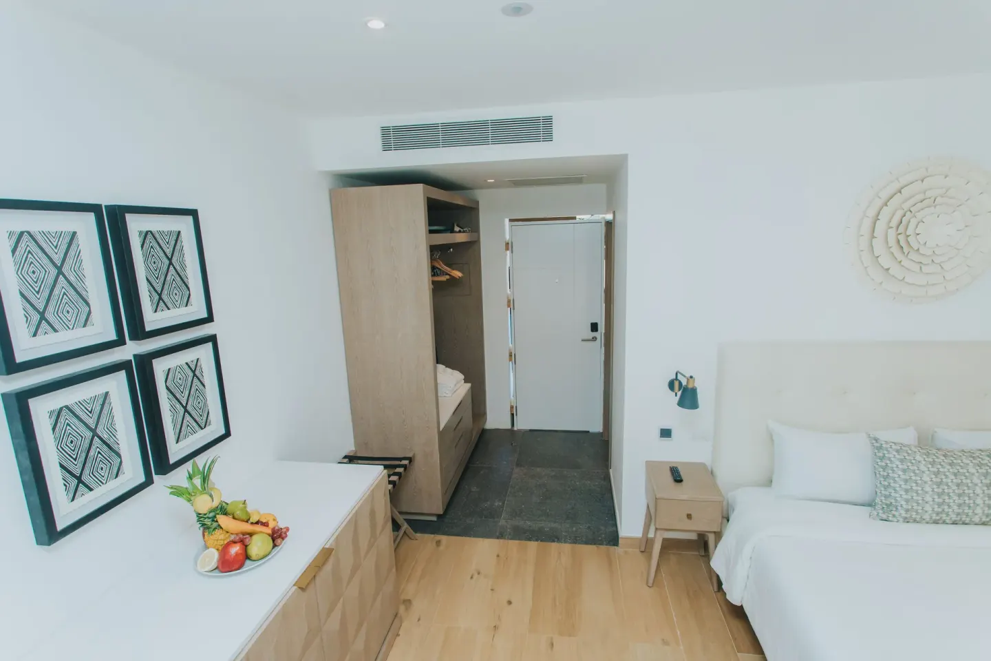 Family Club Junior Suite bedroom with bed, dresser, closet and entry at Princess Family Club Bavaro.