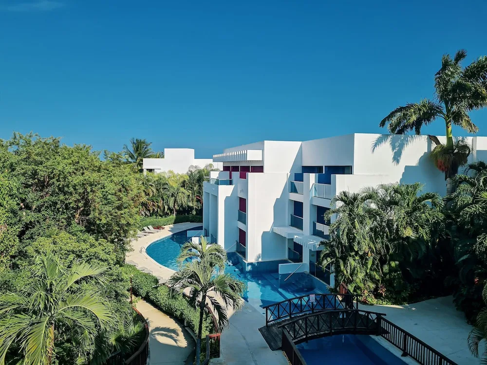 Aerial view of white buildings, pool, palms, and walkway at Princess Family Club Riviera.