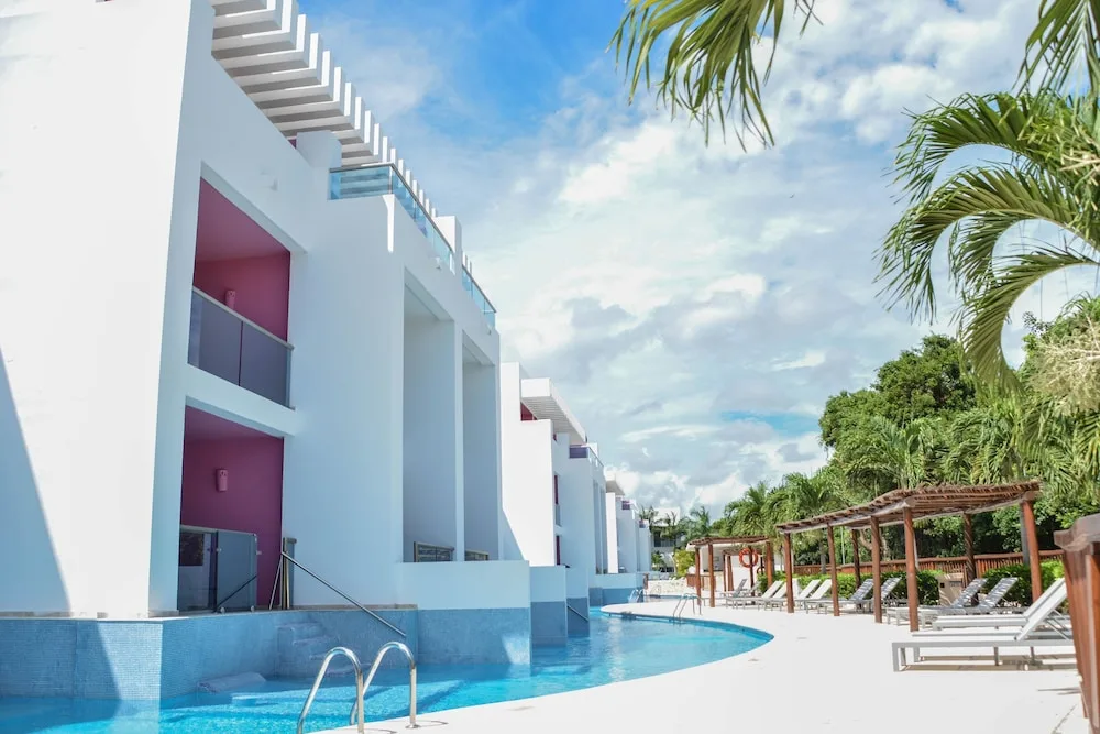 Curving pool beside white guest buildings at Princess Family Club Riviera.