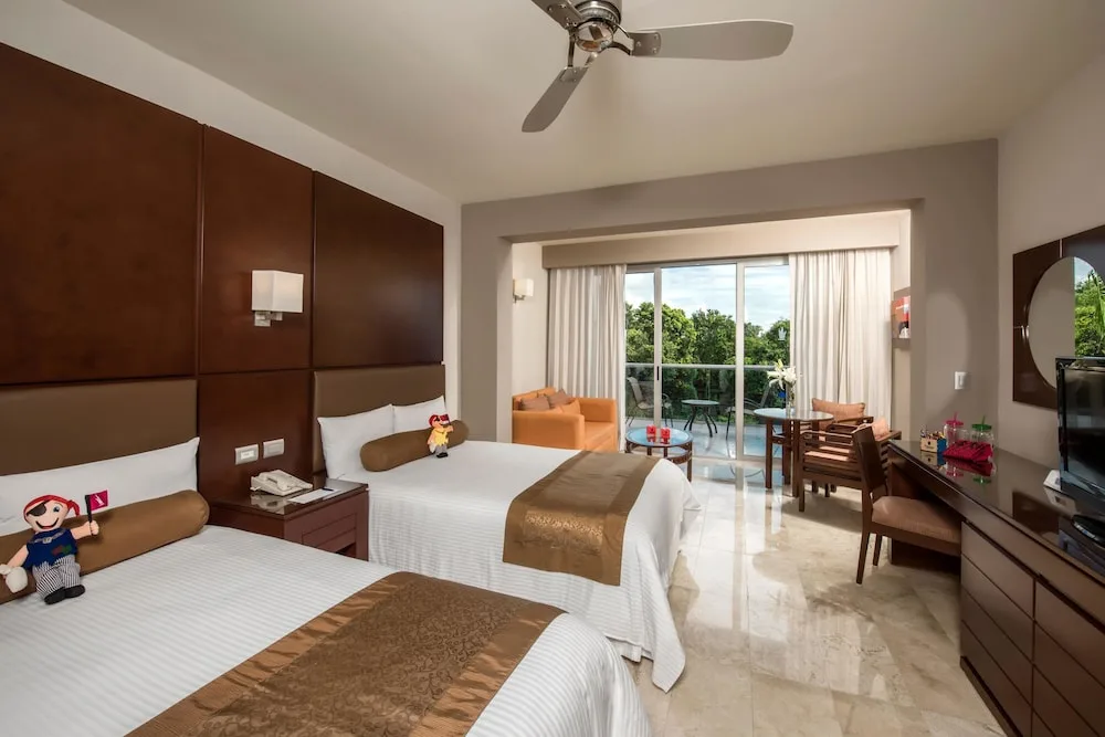 Guest room with two double beds, balcony doors, and desk at Princess Family Club Riviera.