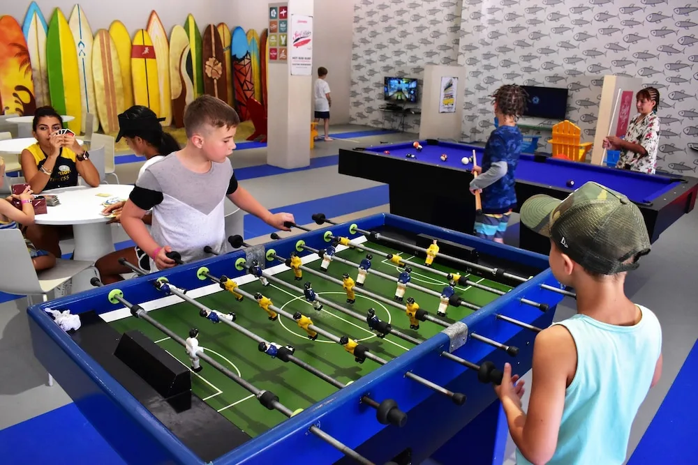 Children play foosball and pool in a colorful game room at Princess Family Club Riviera.