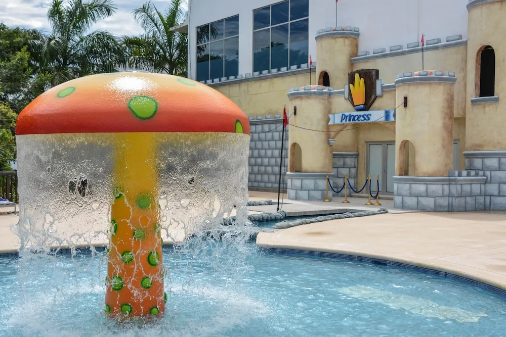 Mushroom fountain splashes beside a castle-themed wall at Princess Family Club Riviera.