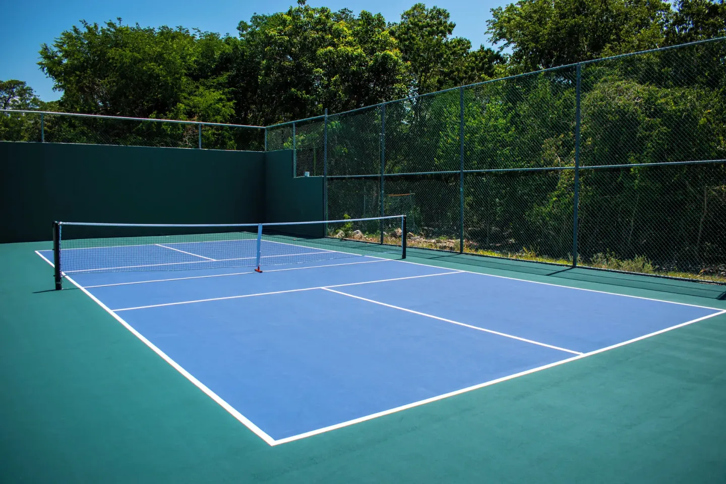 Outdoor pickleball court bordered by fencing and trees at Princess Family Club Riviera.
