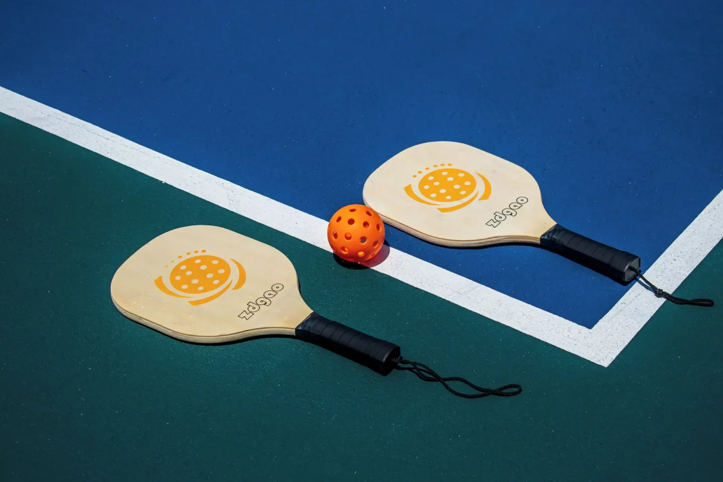 Two pickleball paddles and an orange ball on a court at Princess Family Club Riviera.