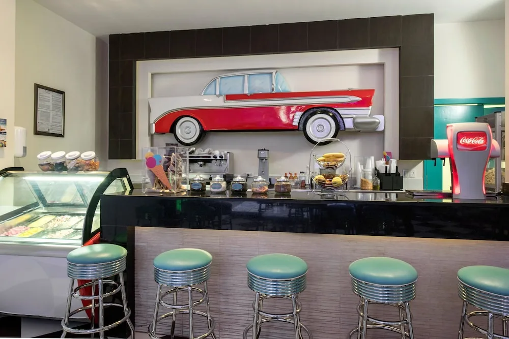 Ice cream and soda counter at Princess Family Club Riviera with teal stools and a red classic car wall feature.