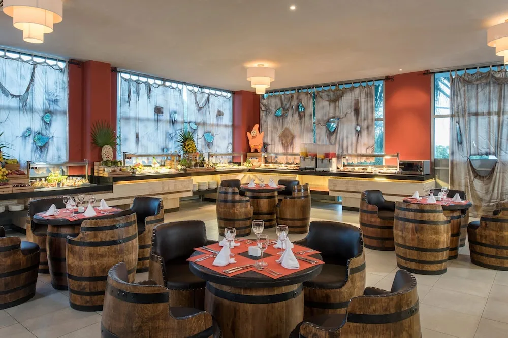 Pirate-themed buffet dining room at Princess Family Club Riviera with barrel-style tables and food stations.