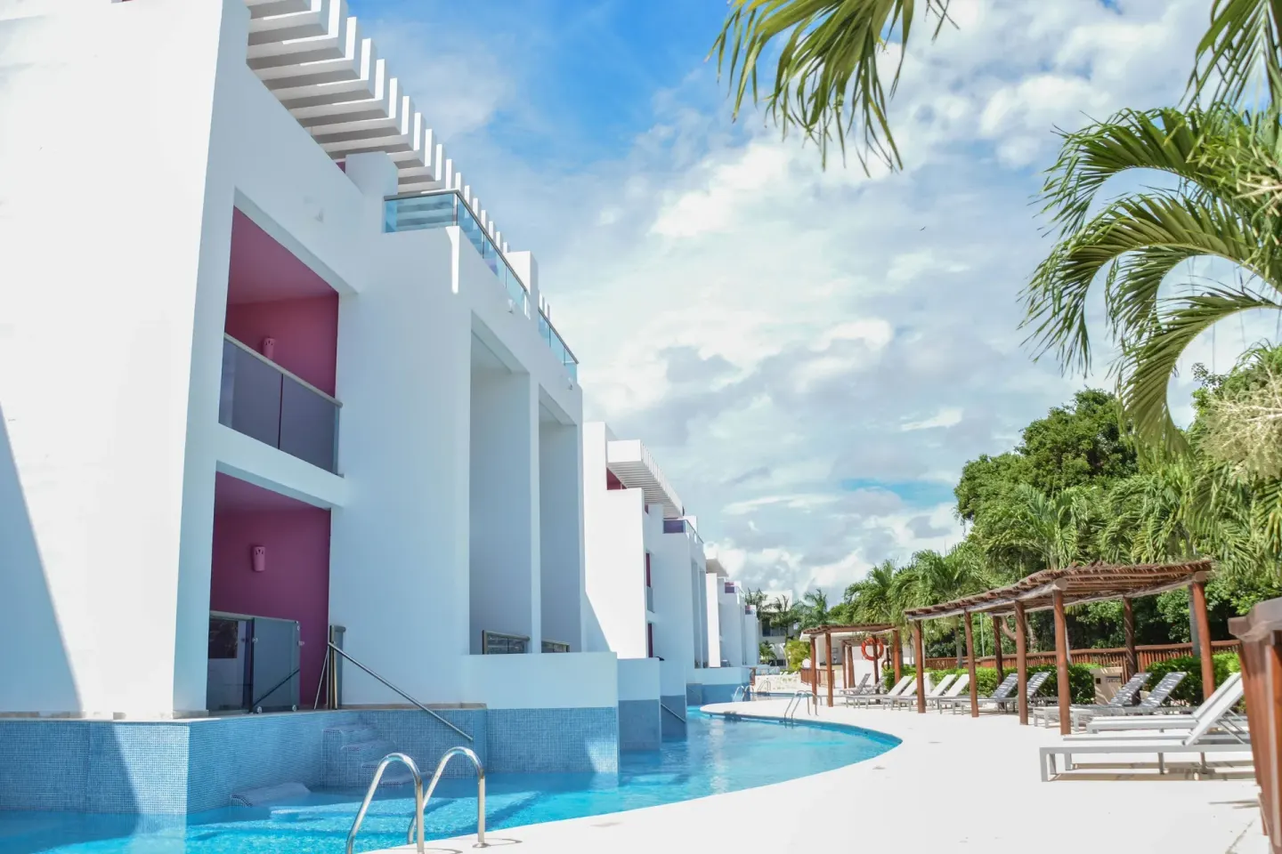 Pool access building at Princess Family Club Riviera with swim-up rooms, loungers and palm trees.