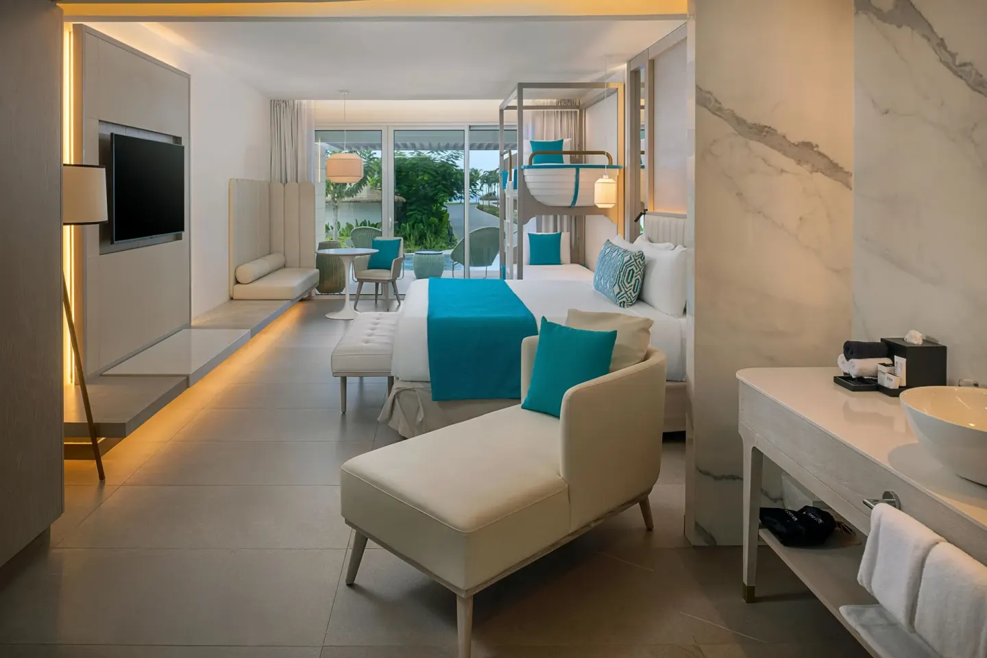 Family guest room with king bed, bunk beds, vanity and TV at Princess Grand Jamaica Resort.