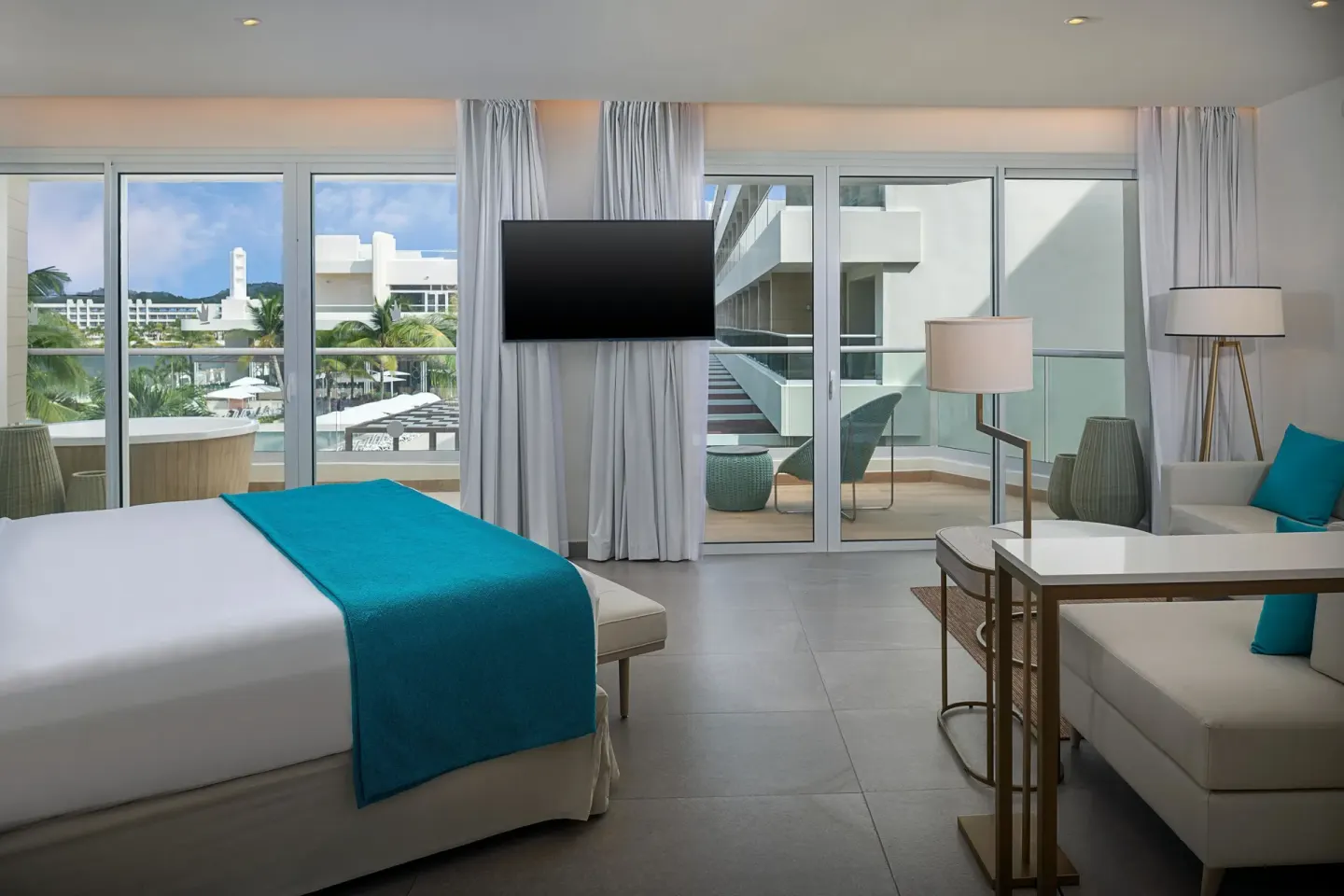 King bed guest room with balcony doors and seating at Princess Grand Jamaica Resort.