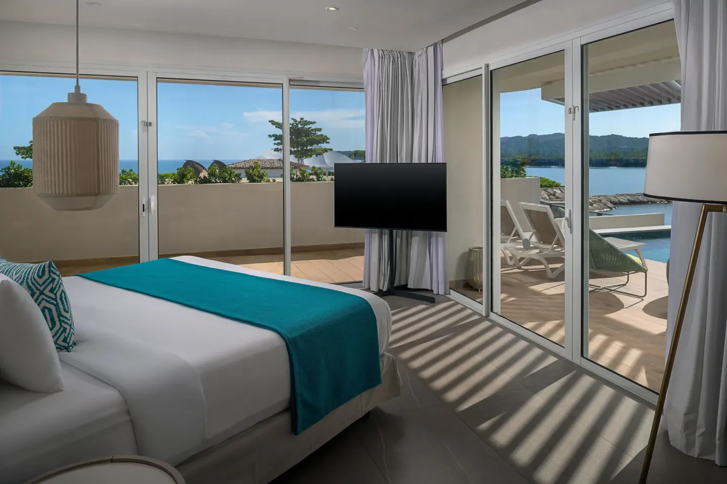 King bed guest room with wraparound terrace and water views at Princess Grand Jamaica Resort.