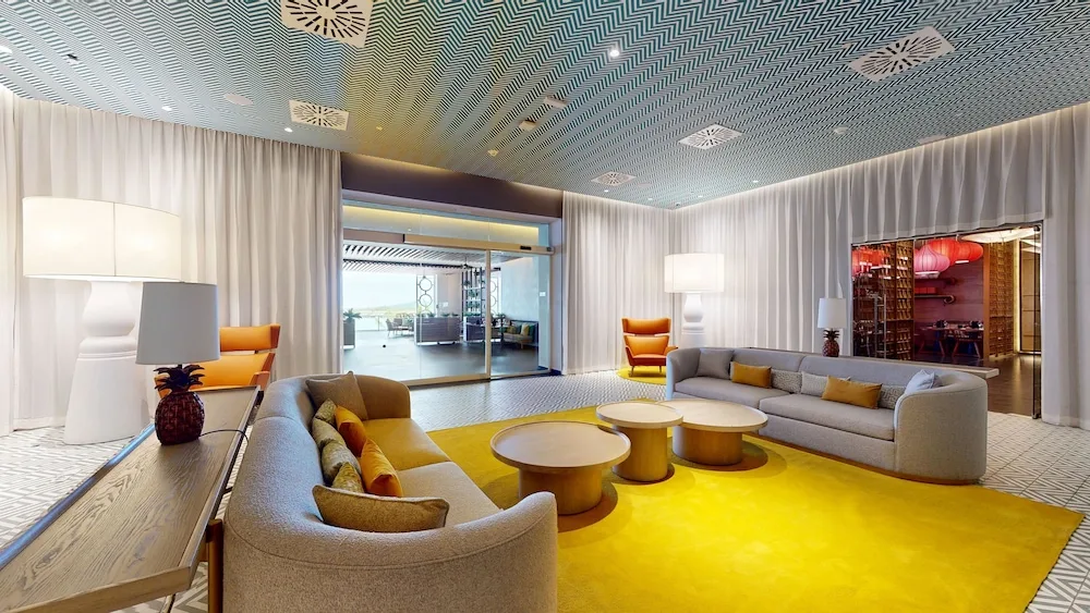 Lobby lounge with curved sofas and yellow rug at Princess Grand Jamaica Resort.