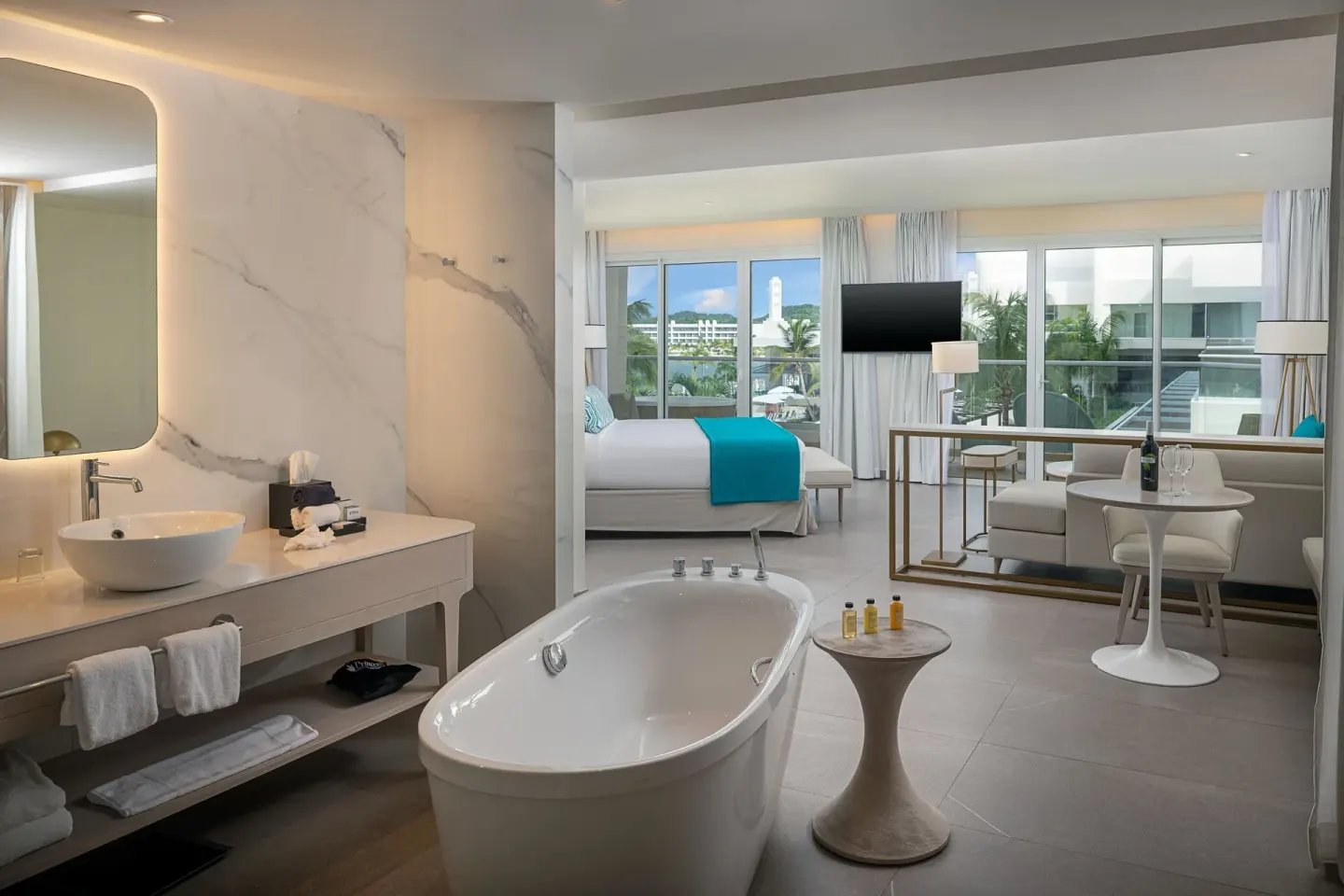 Suite bathroom with freestanding tub and bedroom beyond at Princess Grand Jamaica Resort.