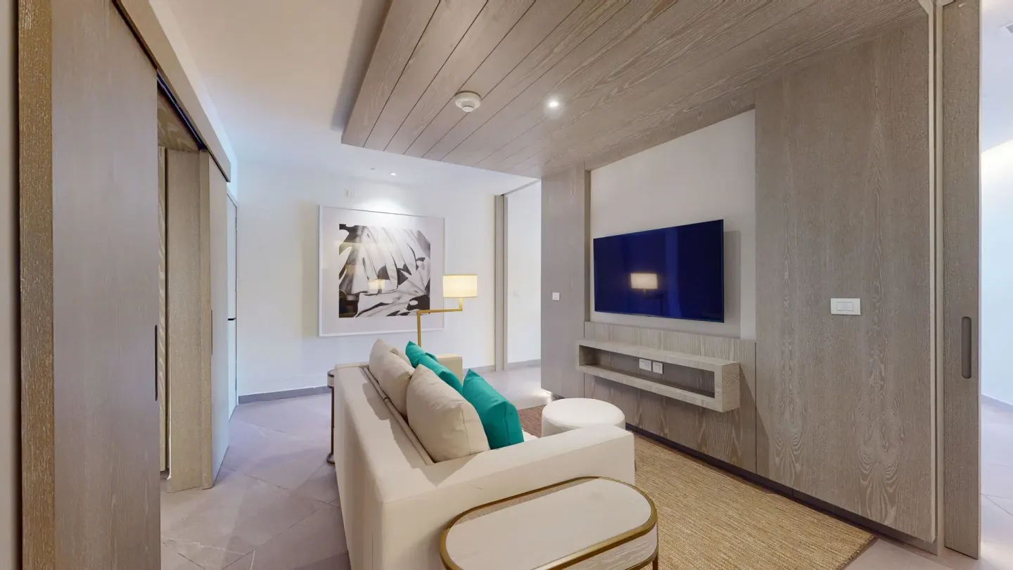 Suite living room with sofa, TV and wood accent wall at Princess Grand Jamaica Resort.