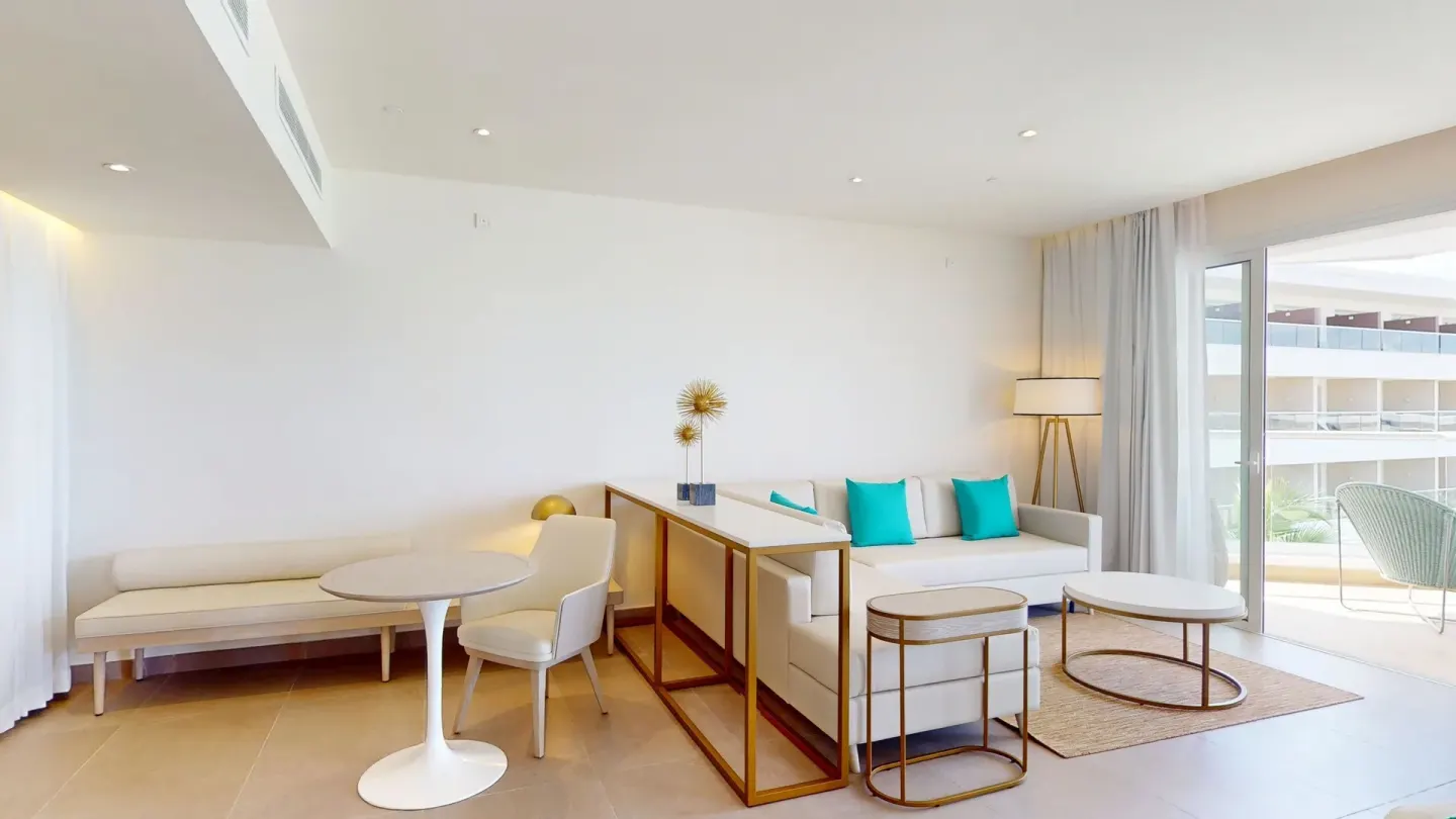 Suite lounge with sofa, dining table and balcony at Princess Grand Jamaica Resort.