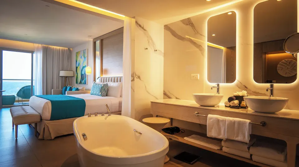 Platinum Junior Suite bath with tub, double vanity and king bed at Princess Grand Jamaica Resort.