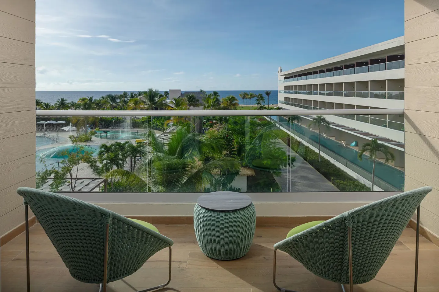 Balcony seating with pool, palm and ocean views from Princess Grand Jamaica Resort.