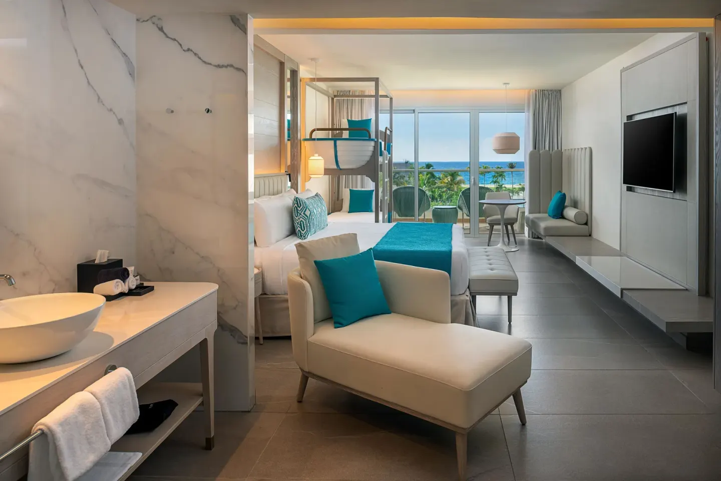 Princess Family Junior Suite with open vanity, king bed, bunk beds and ocean-facing balcony at Princess Grand Jamaica Resort