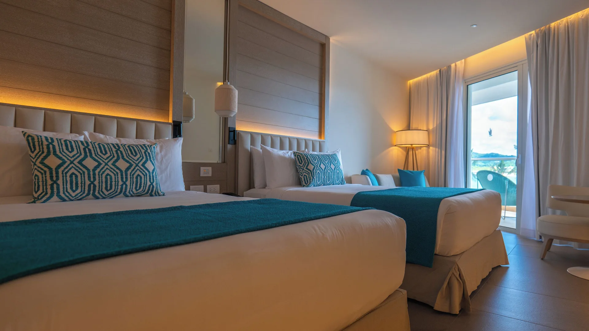 Princess Grand Jamaica Resort with two beds, turquoise accents and balcony doors at Princess Grand Jamaica Resort.