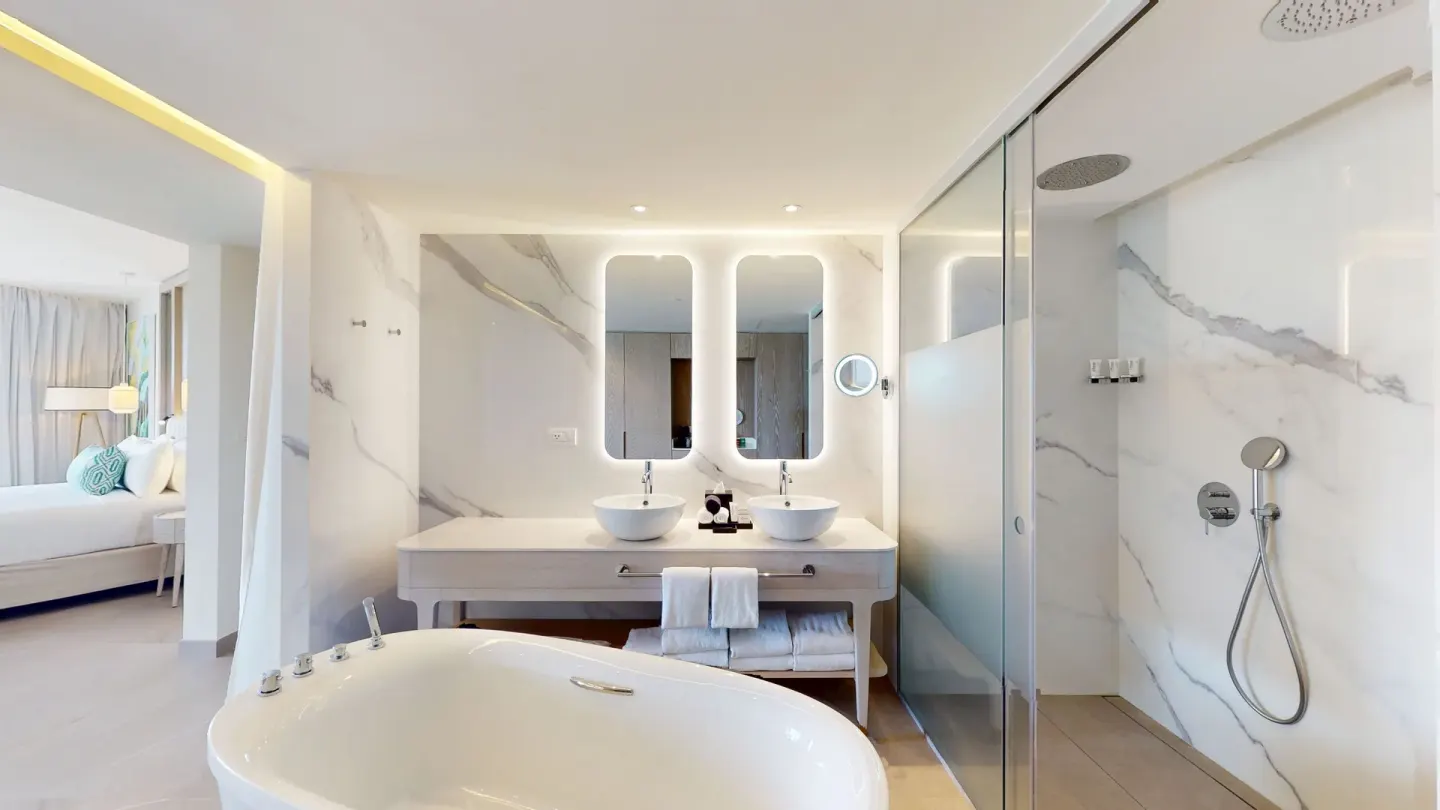 Bathroom with hydromassage tub, double sinks, and glass shower at Princess Grand Jamaica Resort.