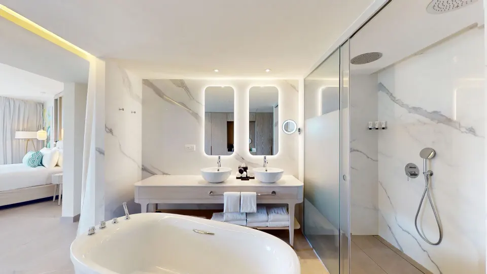 Bathroom with hydromassage tub, double sinks, and glass shower at Princess Grand Jamaica Resort.