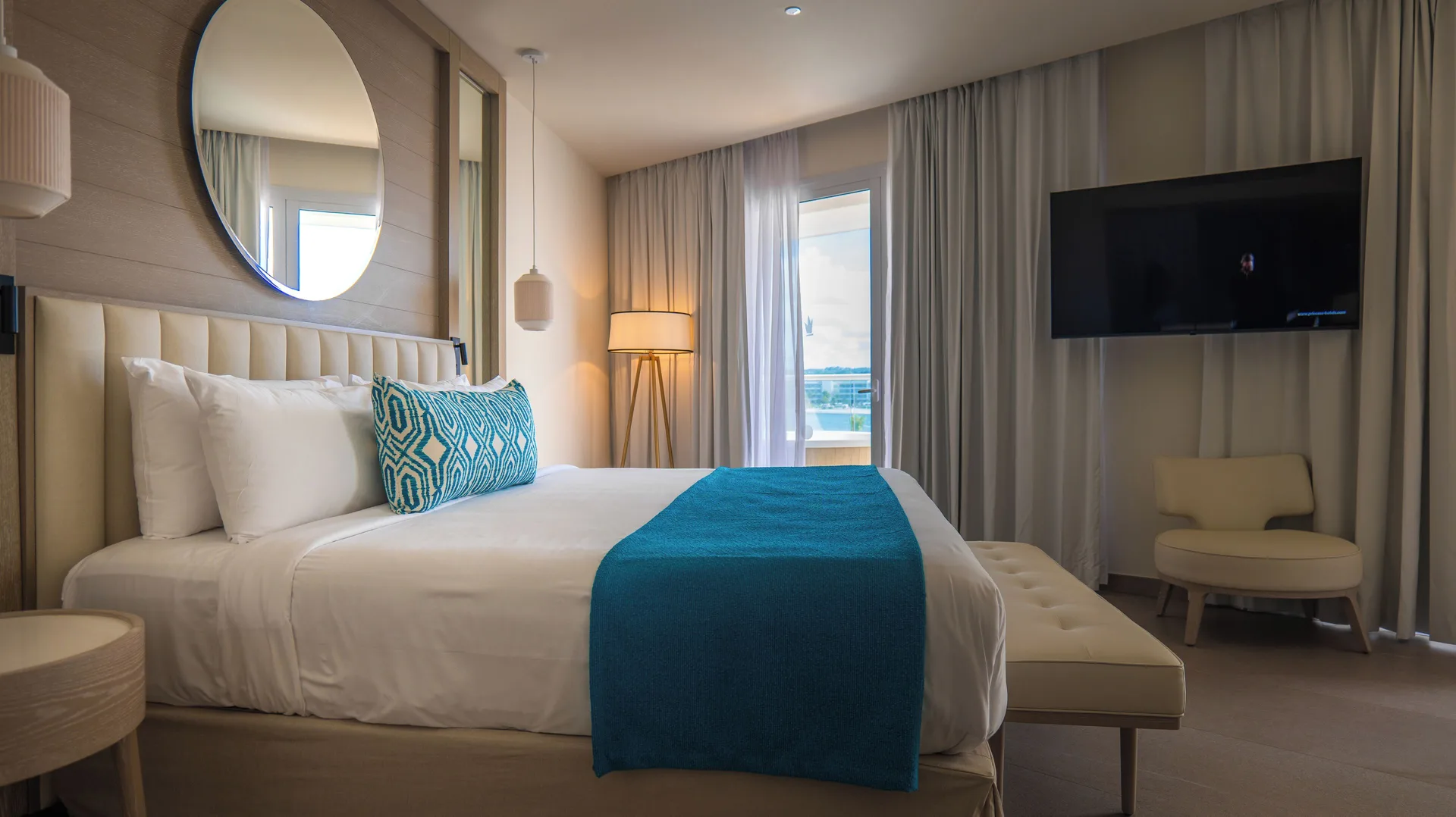 King bed and balcony doors in a Princess Luxury Junior Suite with Hydromassage at Princess Grand Jamaica Resort.