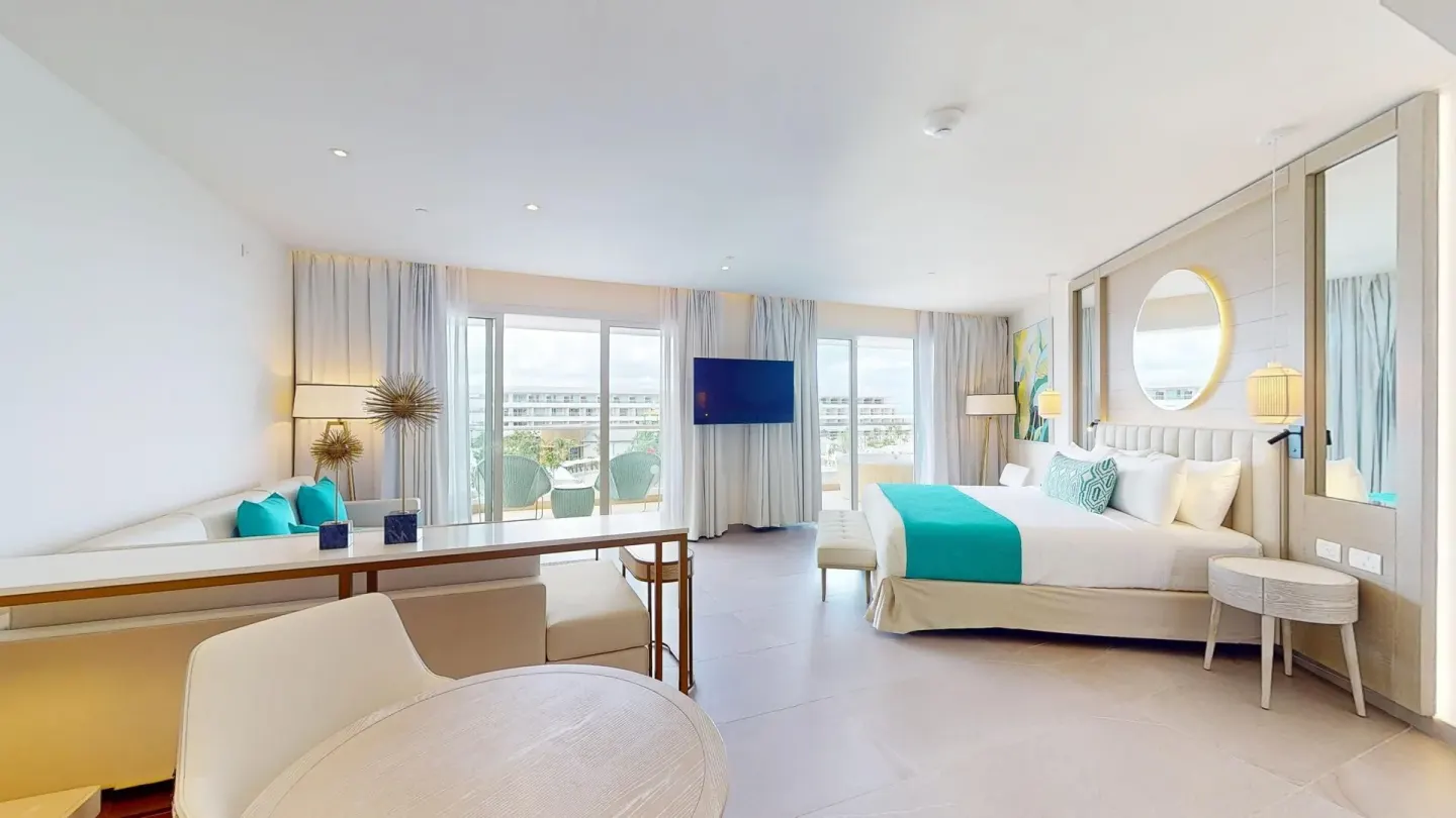 Spacious suite with king bed, sofa, TV, and balcony seating at Princess Grand Jamaica Resort.