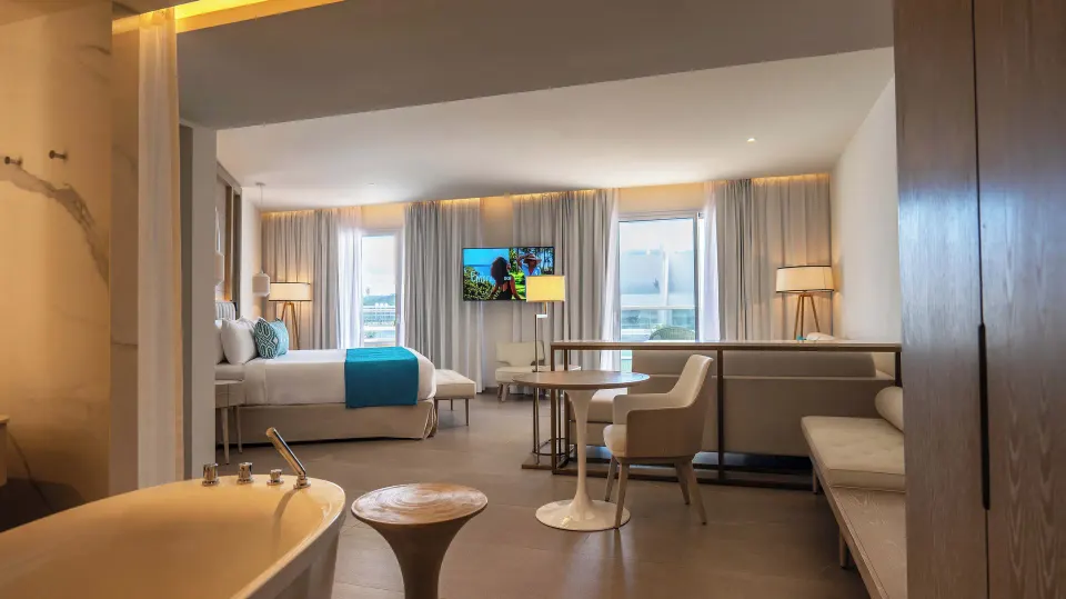 Hydromassage tub, king bed, table, and lounge seating in a suite at Princess Grand Jamaica Resort.