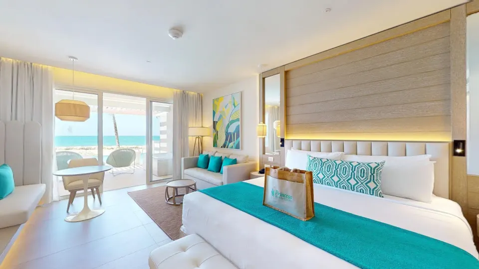 Swim Out Platinum Junior Suite king bed with sofa and ocean-facing terrace at Princess Grand Jamaica Resort.