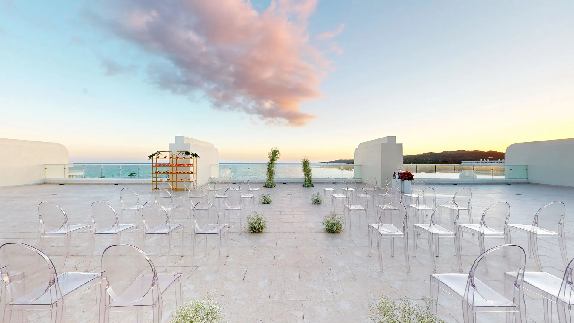 Clear chairs line a sunset rooftop ceremony aisle at Princess Grand Jamaica Resort.