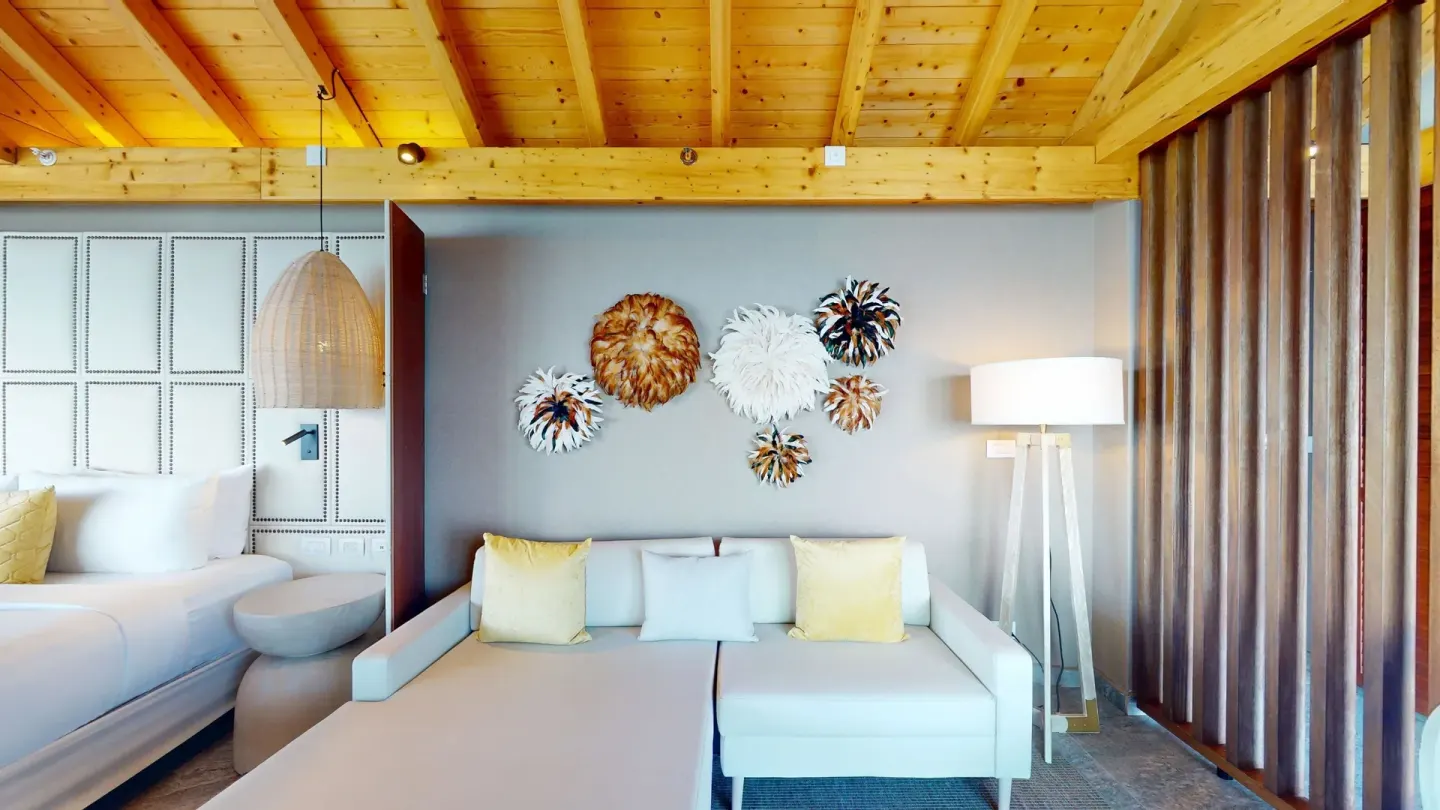 Sofa lounge area beside a guest room bed at Princess Senses The Mangrove Resort.