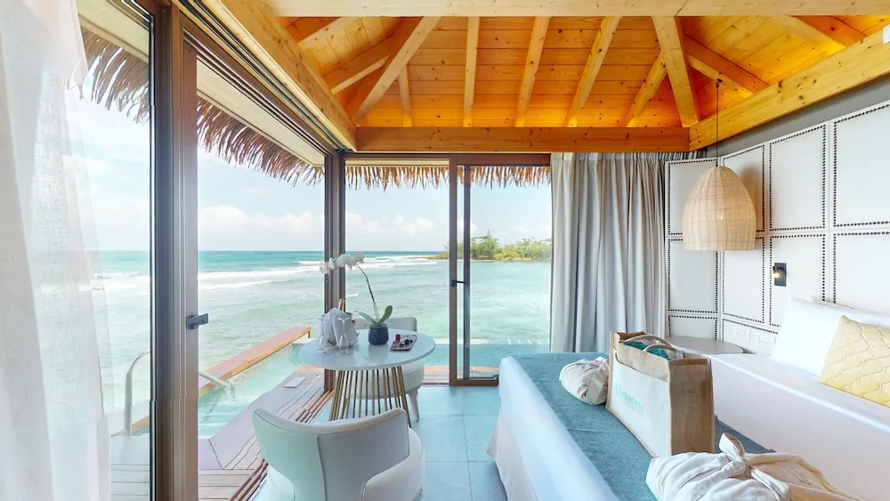 Oceanfront bedroom corner with king bed and glass walls at Princess Senses The Mangrove Resort.