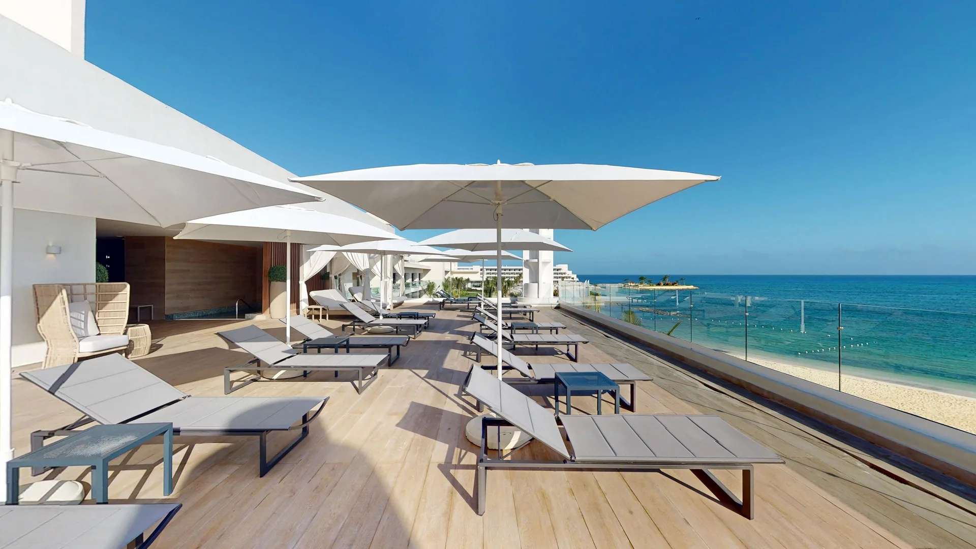 Oceanfront sun deck with loungers and umbrellas at Princess Senses The Mangrove Resort.