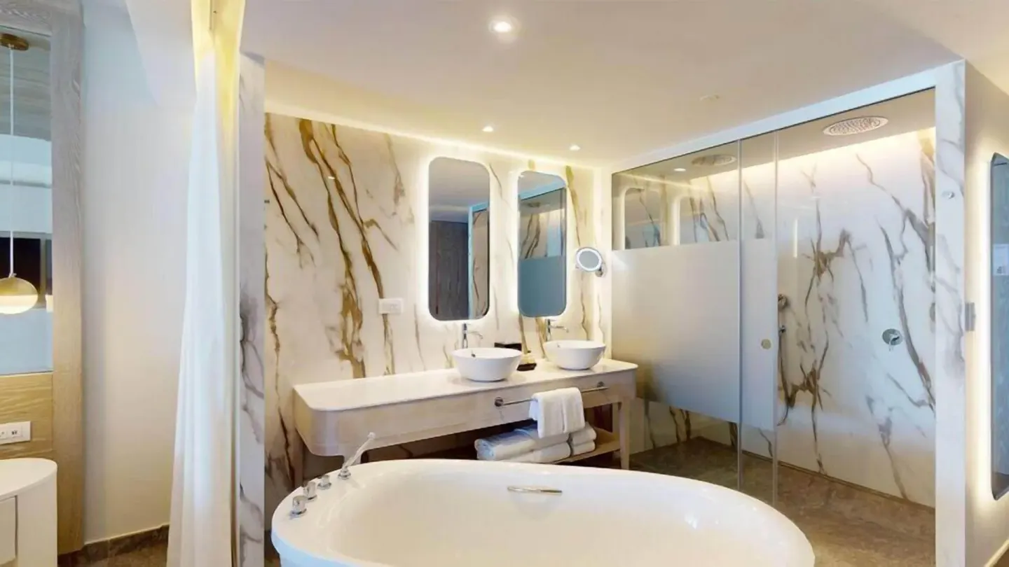 Bathroom with tub and glass shower in a Swim Out Platinum Junior Suite at Princess Senses The Mangrove Resort.
