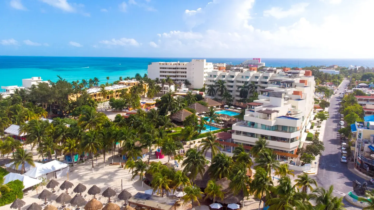 Aerial view of Privilege Aluxes Isla Mujeres near palm trees, beach, and turquoise sea.