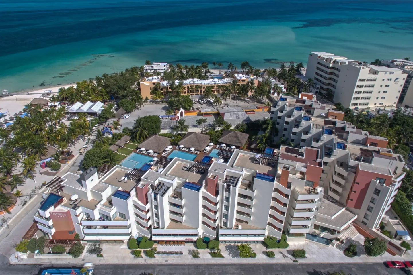 Aerial view of Privilege Aluxes Isla Mujeres buildings, pools, beach, and turquoise water.
