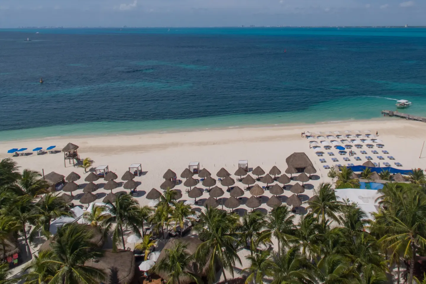 Beach palapas and loungers along the water at Privilege Aluxes Isla Mujeres.