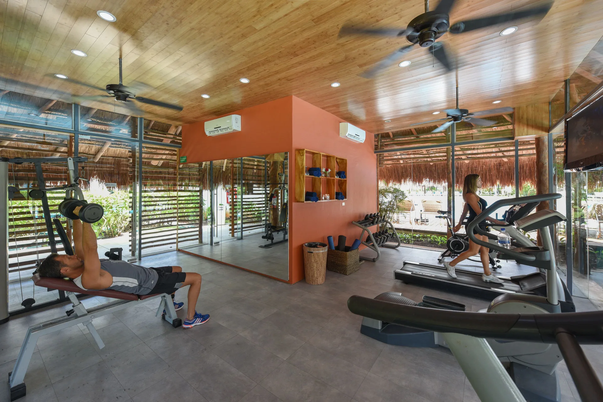 Fitness room with treadmills, weights, and guests exercising at Privilege Aluxes Isla Mujeres.