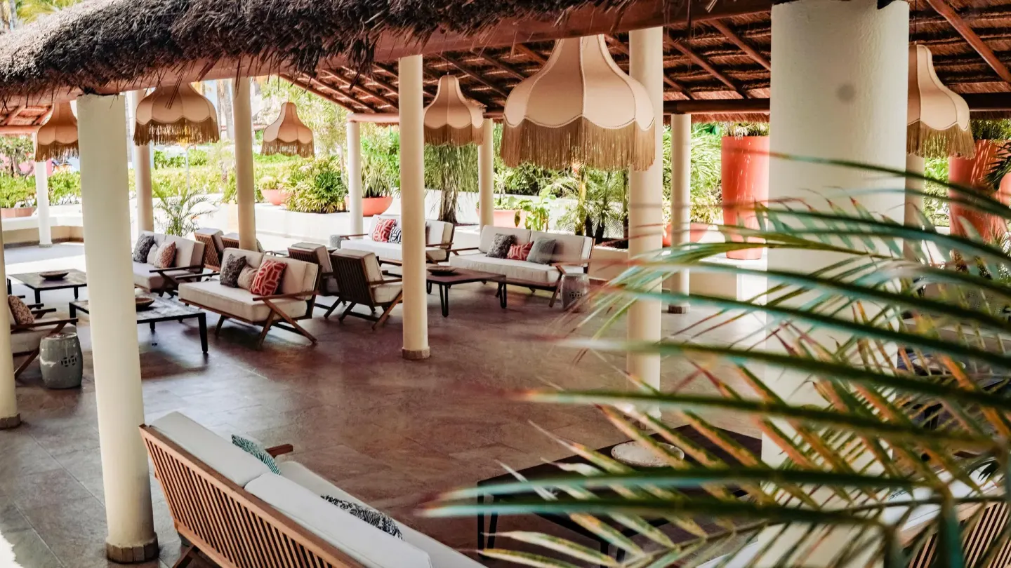 Open-air lounge with sofas under a thatched roof at Privilege Aluxes Isla Mujeres.