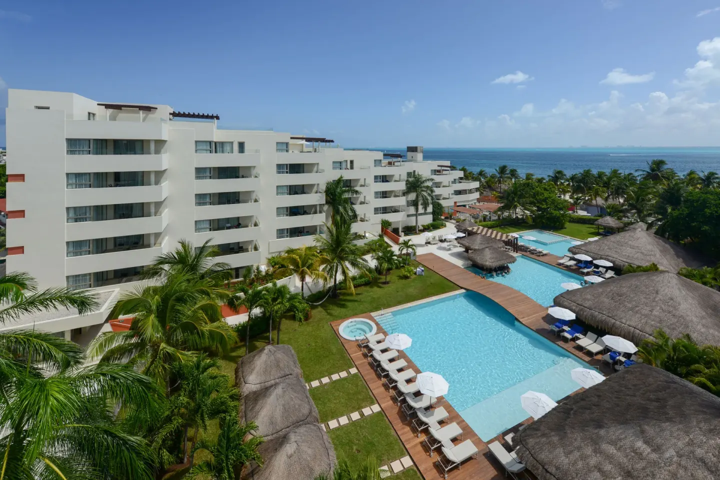 Pool courtyard and white guest-room buildings at Privilege Aluxes Isla Mujeres.