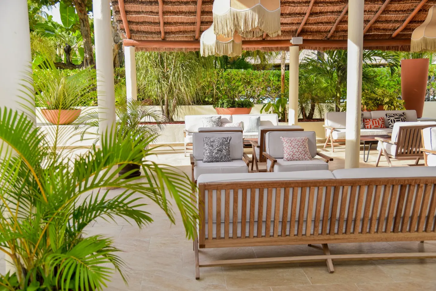 Shaded garden lounge seating at Privilege Aluxes Isla Mujeres with palms and cushioned chairs.