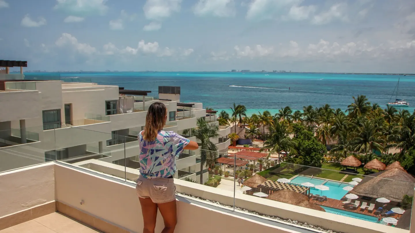 Guest on a terrace overlooking pools and the sea at Privilege Aluxes Isla Mujeres.