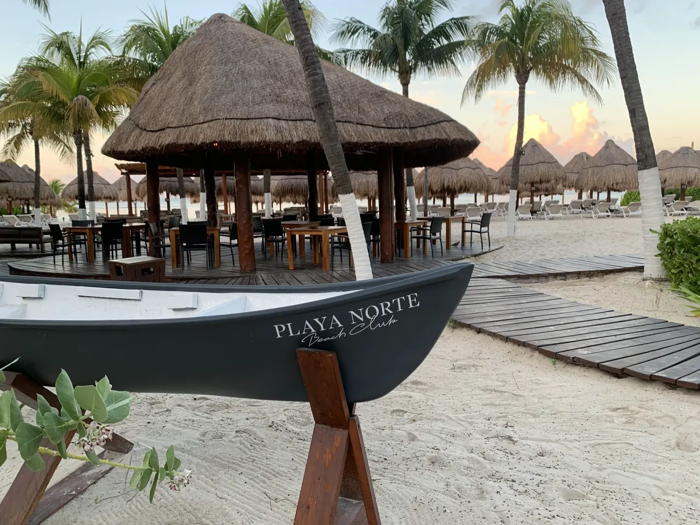 Thatched beach seating and a decorative boat at Privilege Aluxes Isla Mujeres.